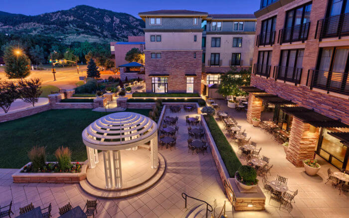 Large modern stone building at night with mountains in background.