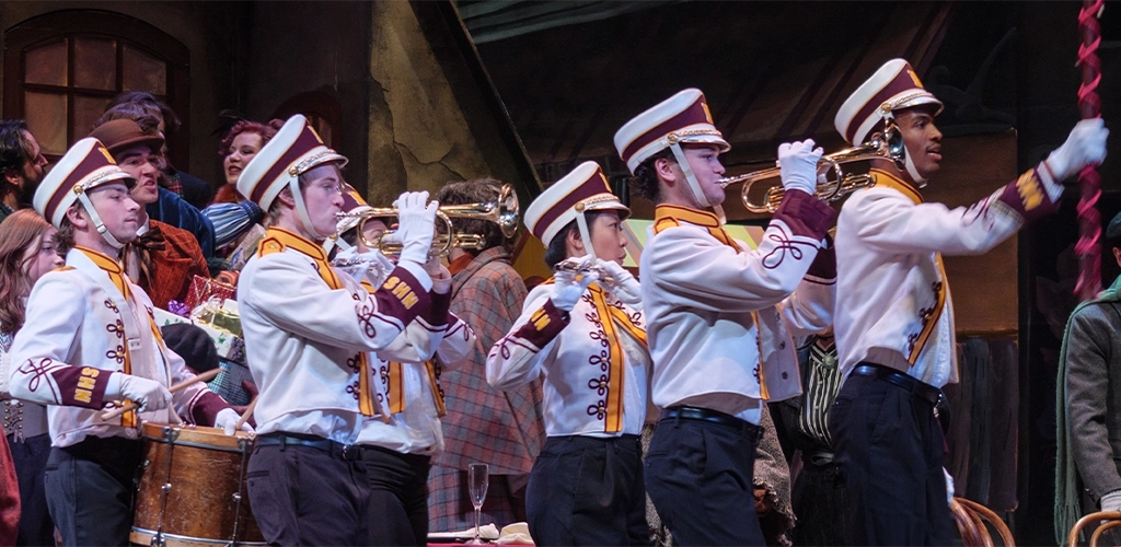 Members of a marching band marching playing brass instru,ents